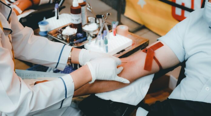 Profissional de saúde com luvas brancas coletando sangue do braço de um doador